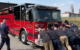 Firefighters Push A New Fire Truck Into A Fire Station