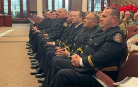 Ten Dalton Firefighters in dress uniforms sit on the front row of a meeting in the City Council Chambers 