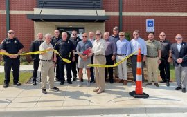 Mayor Annalee Sams (center) cuts a piece of crime scene tape to officially dedicate the new Property and Evidence building