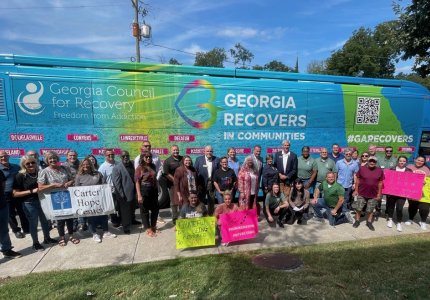 A crowd of Dalton leaders and state Council For Recovery participants pose next to the Georgia Recovers Bus 
