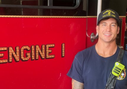 Dalton firefighter Andrew Carlson poses next to a fire engine 