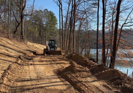 A crewmember from the Dalton Public Works Department works to clear a path for the paving project in Haig Mill Lake Park