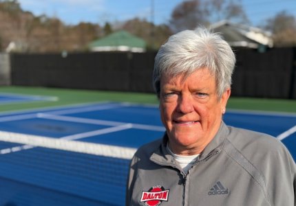 A portrait of DPRD Tennis and Pickleball Director Michel Bates on a tennis court 