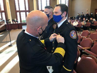 Fire Chief Todd Pangle pins a badge on Captain Dan Hudson