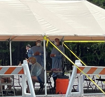Personnel take shelter from the hot afternoon sun under a tent at the Regeneron treatment drive-in clinic on Friday afternoon.