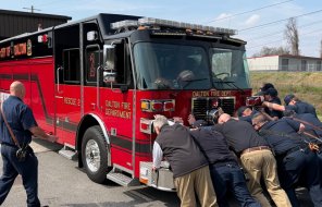 Firefighters Push A New Fire Truck Into A Fire Station