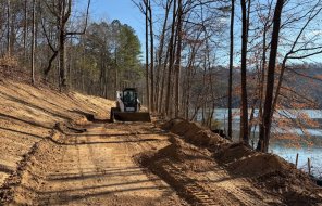 A crewmember from the Dalton Public Works Department works to clear a path for the paving project in Haig Mill Lake Park