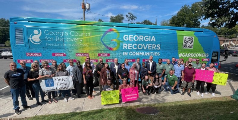 A crowd of Dalton leaders and state Council For Recovery participants pose next to the Georgia Recovers Bus 