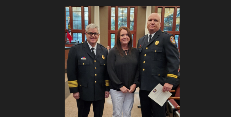 Battalion Chief Chad Young (right) poses with his wife Angela and Fire Chief Matt Daniel (left) after receiving his promotion Tu