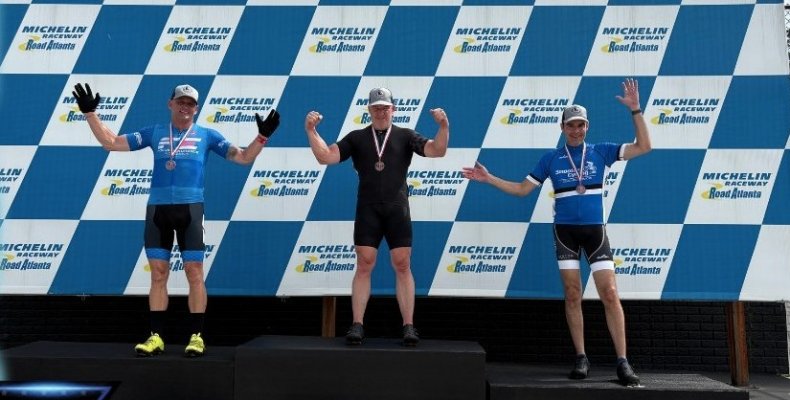 Dalton firefighter Douglas Kerns (left) stands on the awards podium after finishing second in the cyclinc competition at the Mic